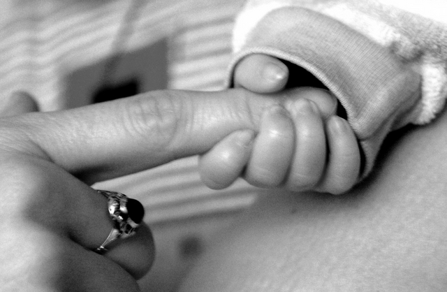 tiny baby hand holding adult's finger